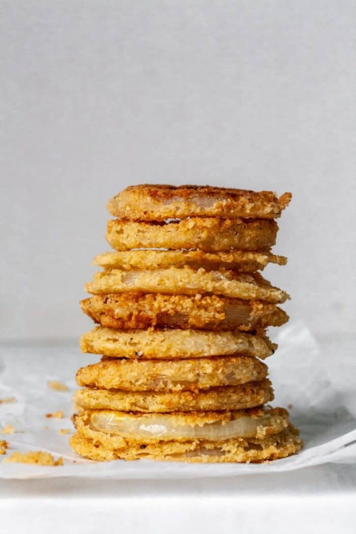 A stack of onion rings on white parchment paper.