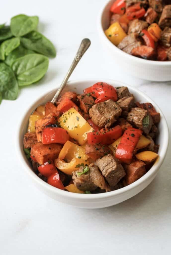 Whole30 garlic steak bites with potatoes in a white bowl.