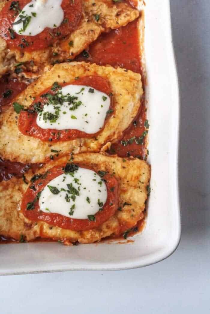 A white casserole dish with Whole30 Chicken Parmesan.