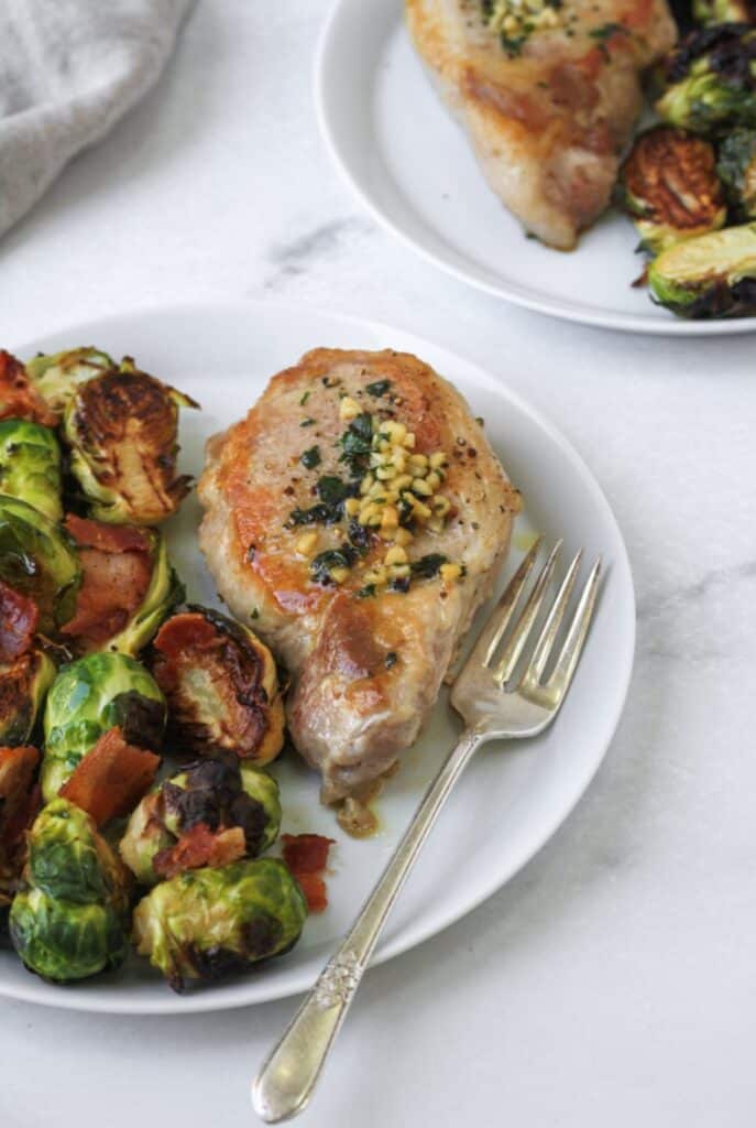 Whole30 Pork Chops on a white plate with Brussels sprouts.