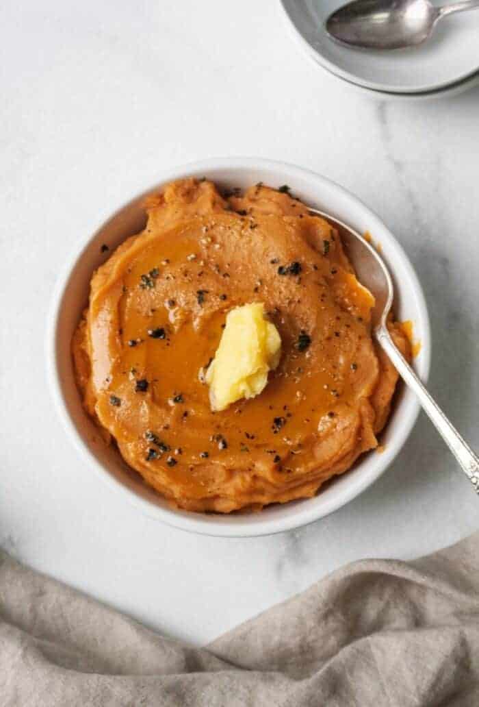 A bowl of mashed sweet potatoes topped with ghee.