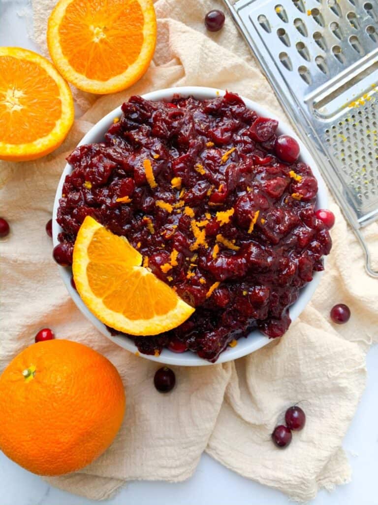 Paleo cranberry sauce in bowl with sliced orange