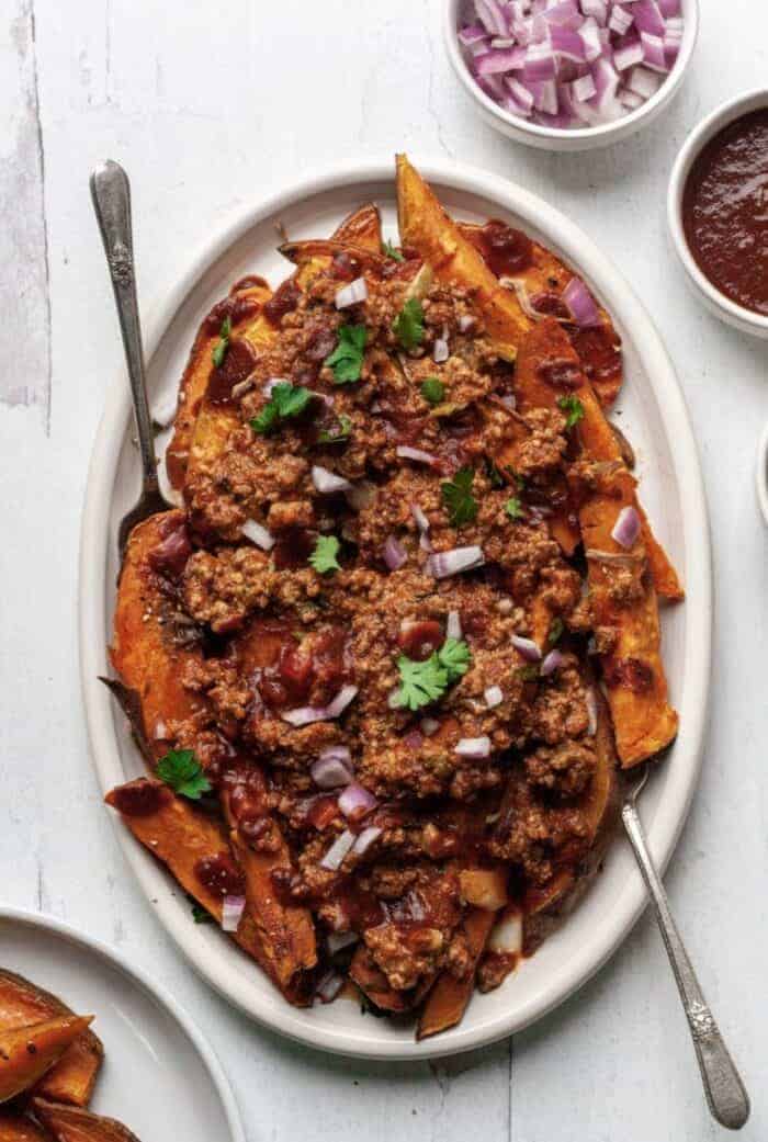 A white plate topped with sweet potato fries and homemade chili.