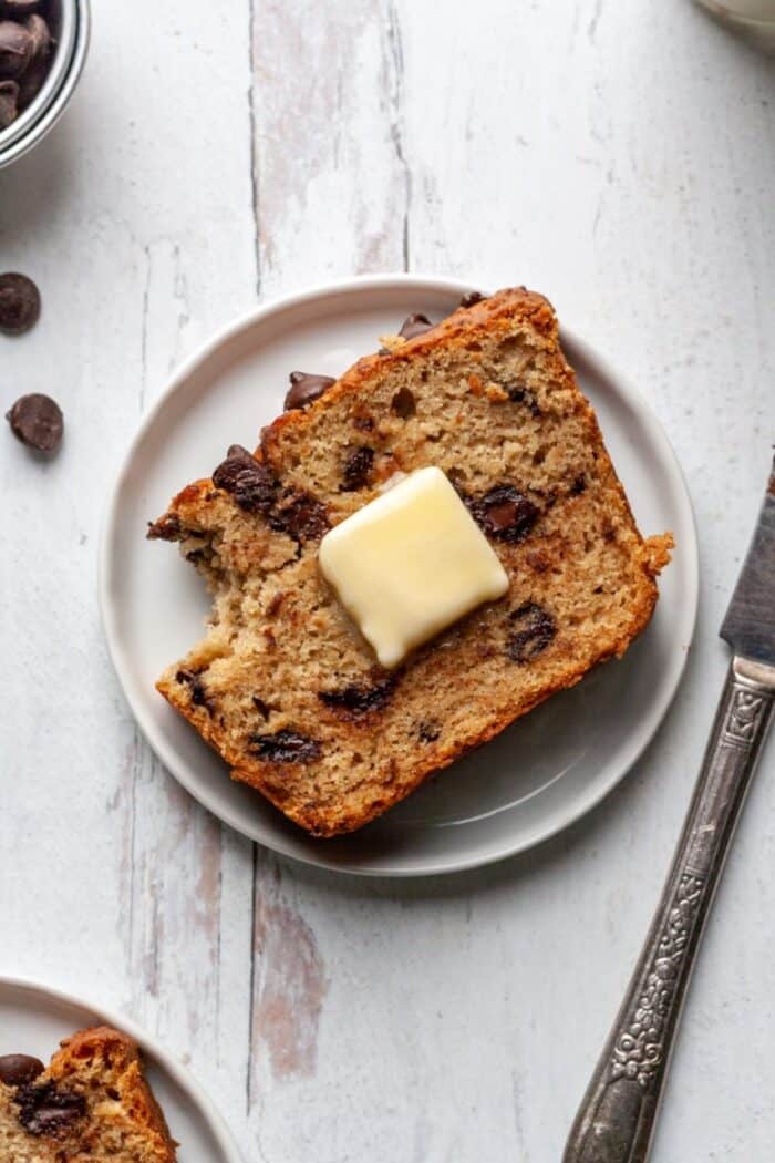 A piece of gluten free chocolate chip banana bread on a white plate.