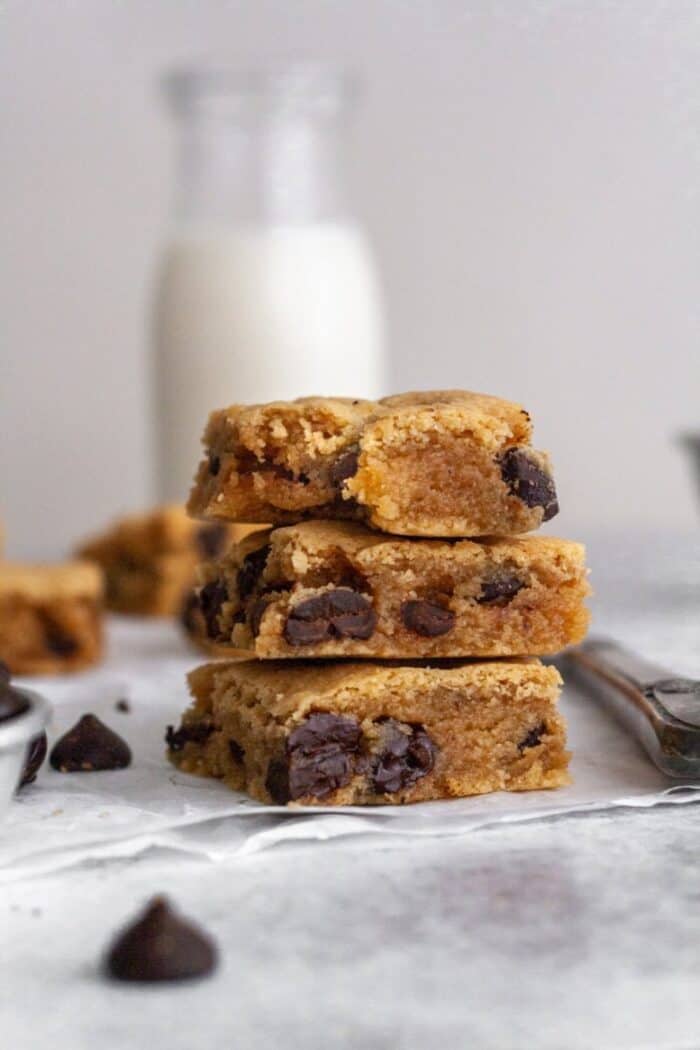 A stack of Paleo Gluten Free Blonde Brownies with a glass of milk.