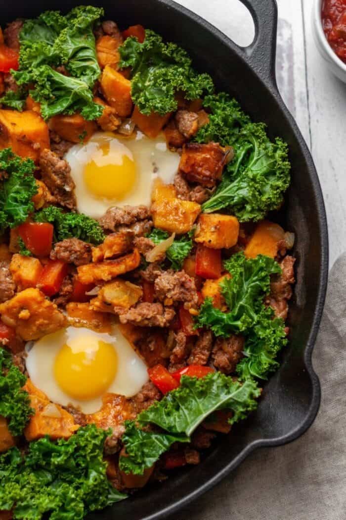 A cast iron skillet filled with veggies and eggs.