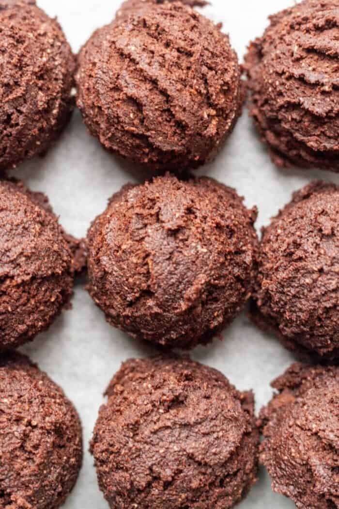 Paleo Brownie Cookie dough balls on a sheet of white parchment paper.