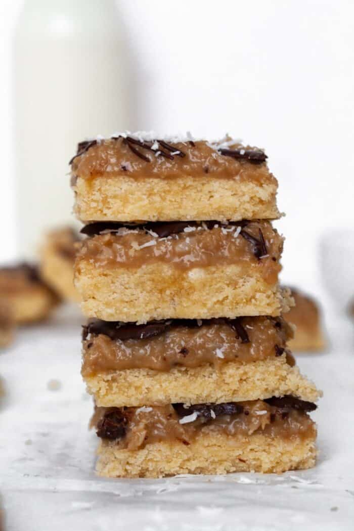 A stack of four Samoa bars with a glass of milk in the background.