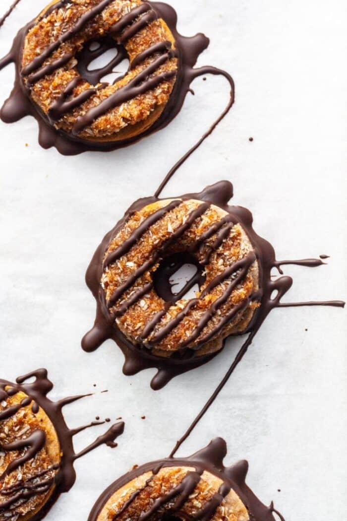 Samoa cookies drizzled with chocolate on white parchment paper.