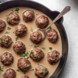 A cast iron skillet filled with meatballs and gravy.