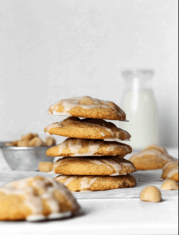 A stack of macadamia nut cookies with a glass of milk in the background.