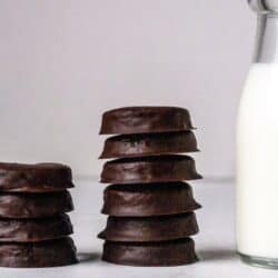 A stack of gluten free Thin Mints with a glass of milk.