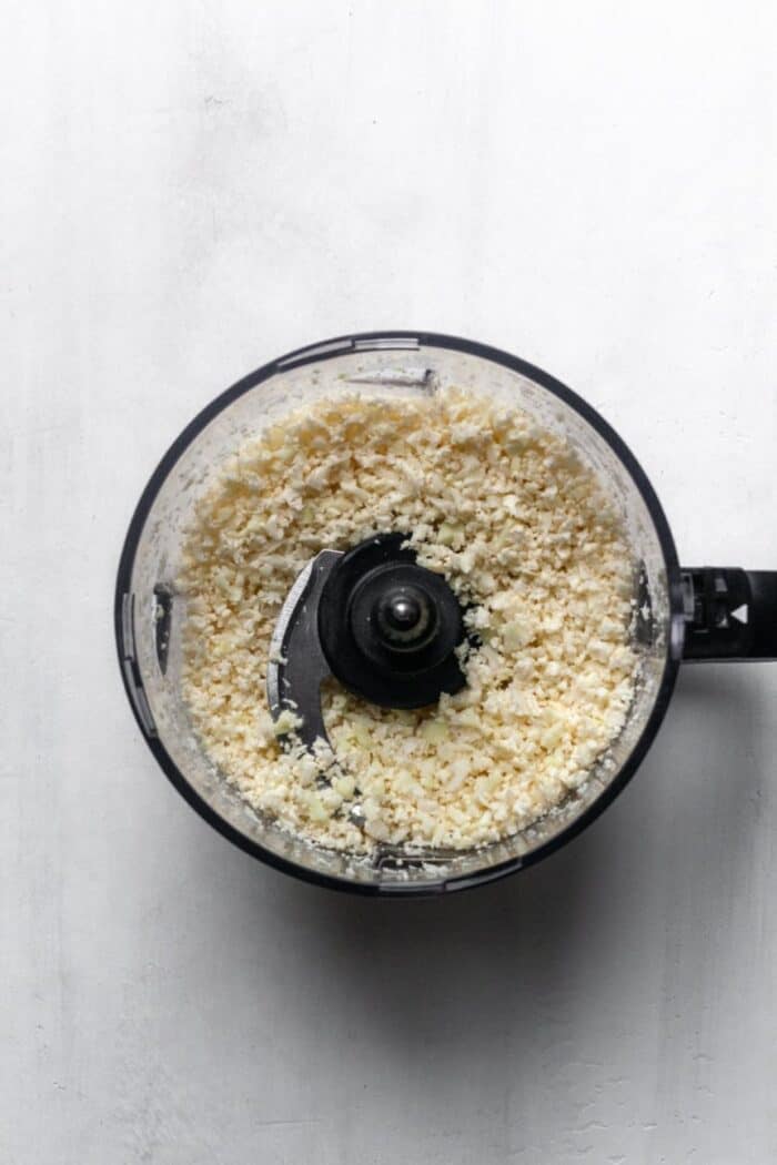 A food processor filled with riced cauliflower.