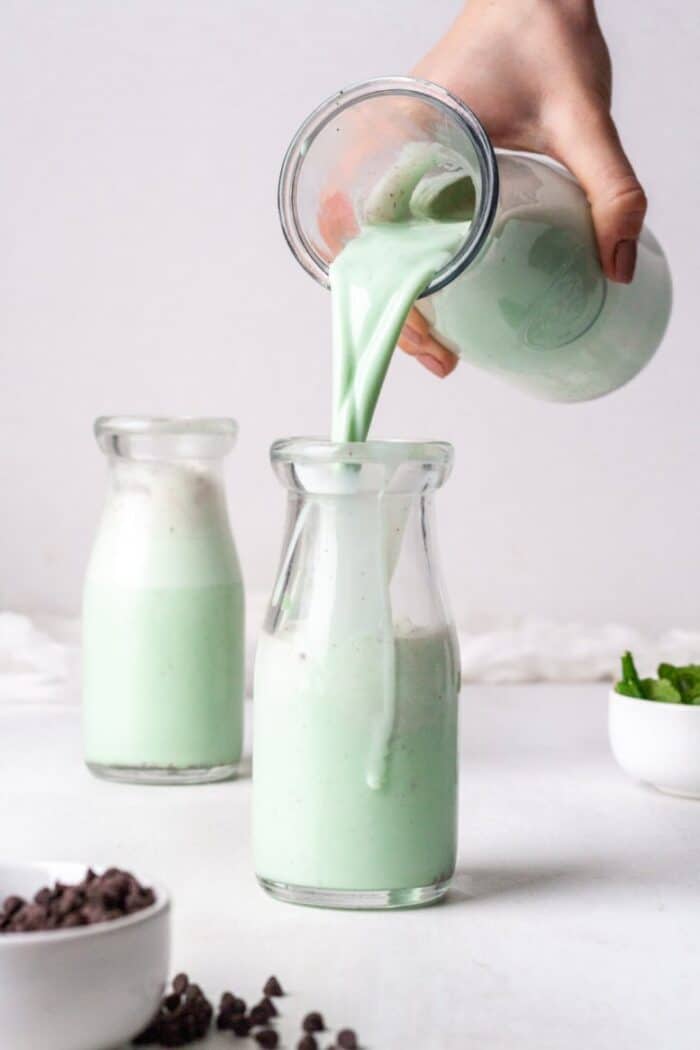 Mint chocolate smoothie being poured into a glass jar.