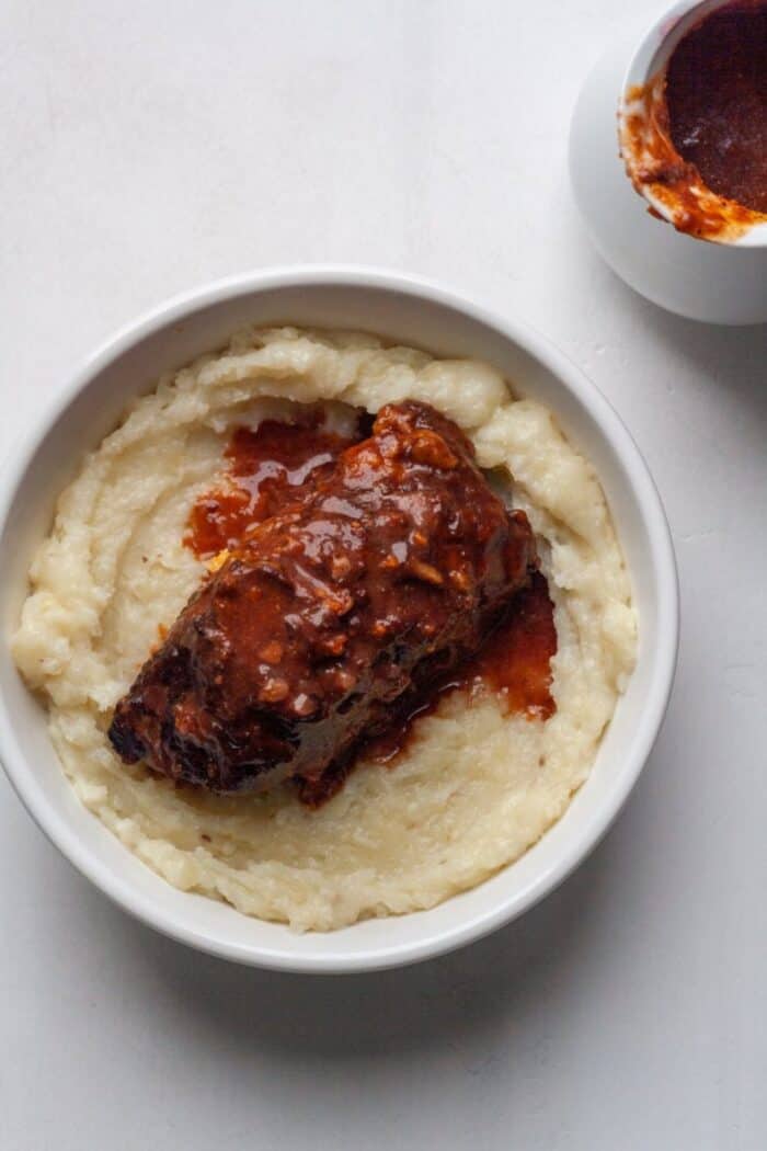 Paleo Braised Short ribs in a white bowl with Whole30 mashed cauliflower.
