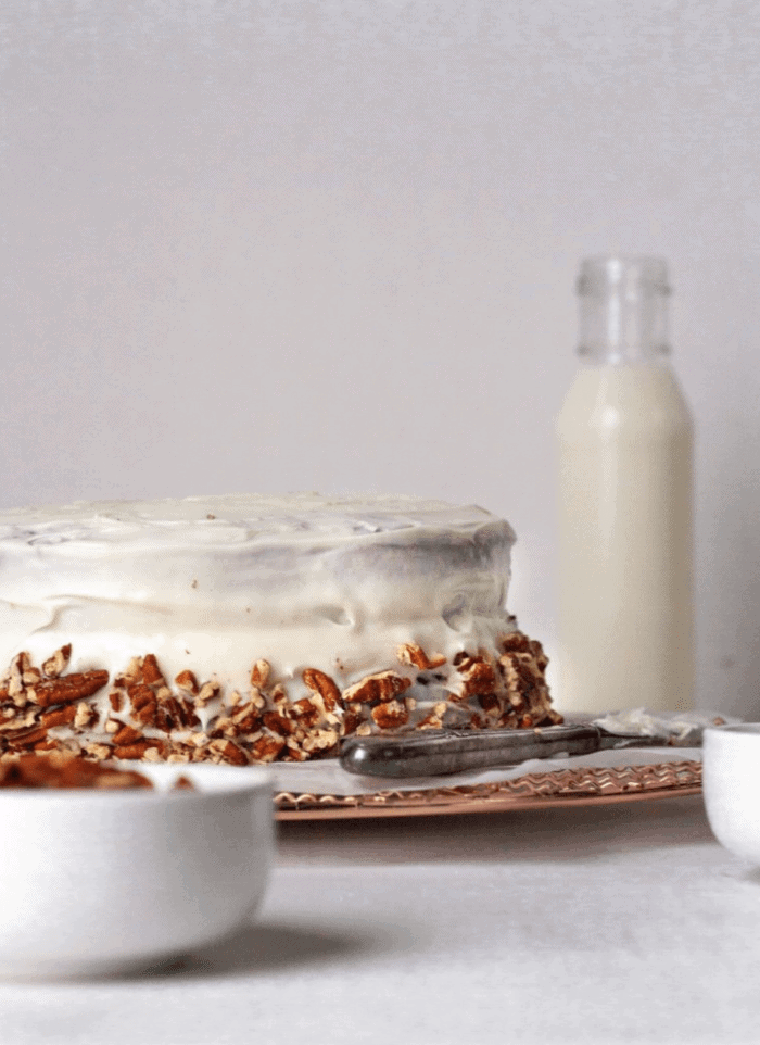 A Paleo Hummingbird cake on a white backdrop with a glass of milk.