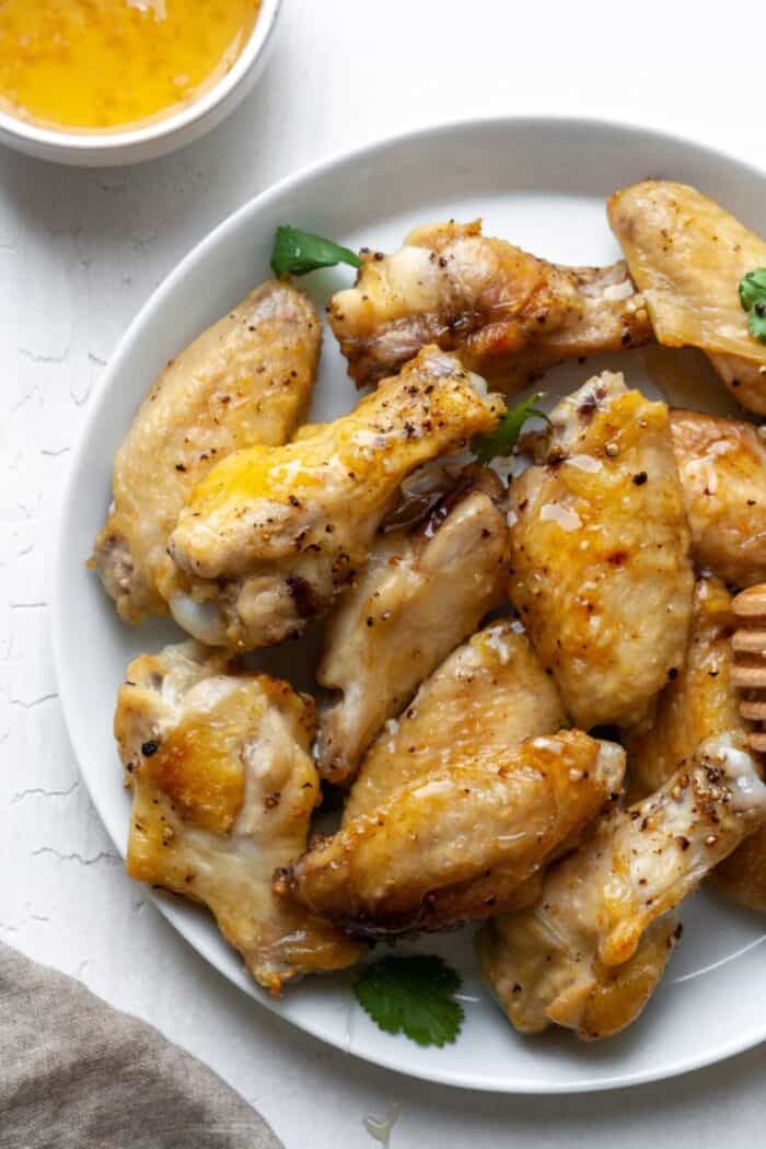 Honey garlic chicken wings on a white plate.