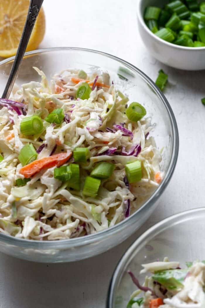 Coleslaw with chopped green onions in a bowl.