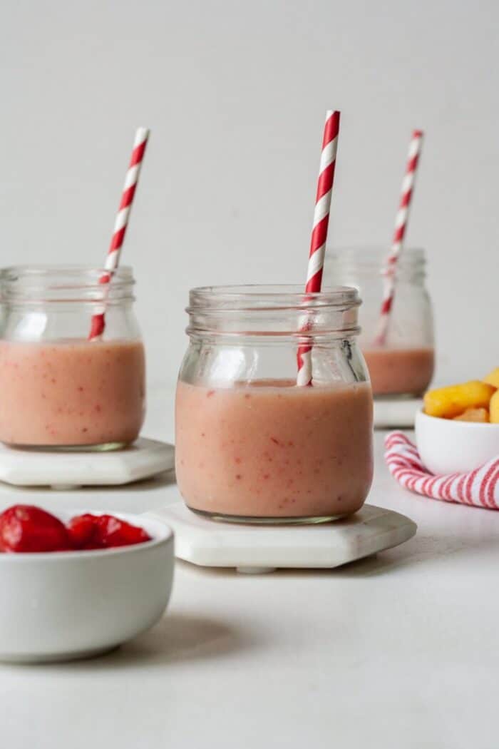 Strawberry pineapple smoothie in glass with straw