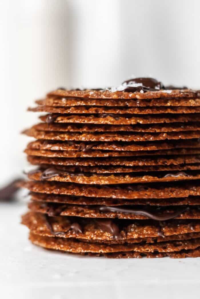 A stack of lace cookies with chocolate drizzle