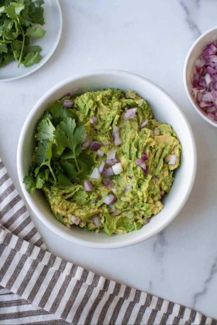 AIP guacamole in white bowl with red onions