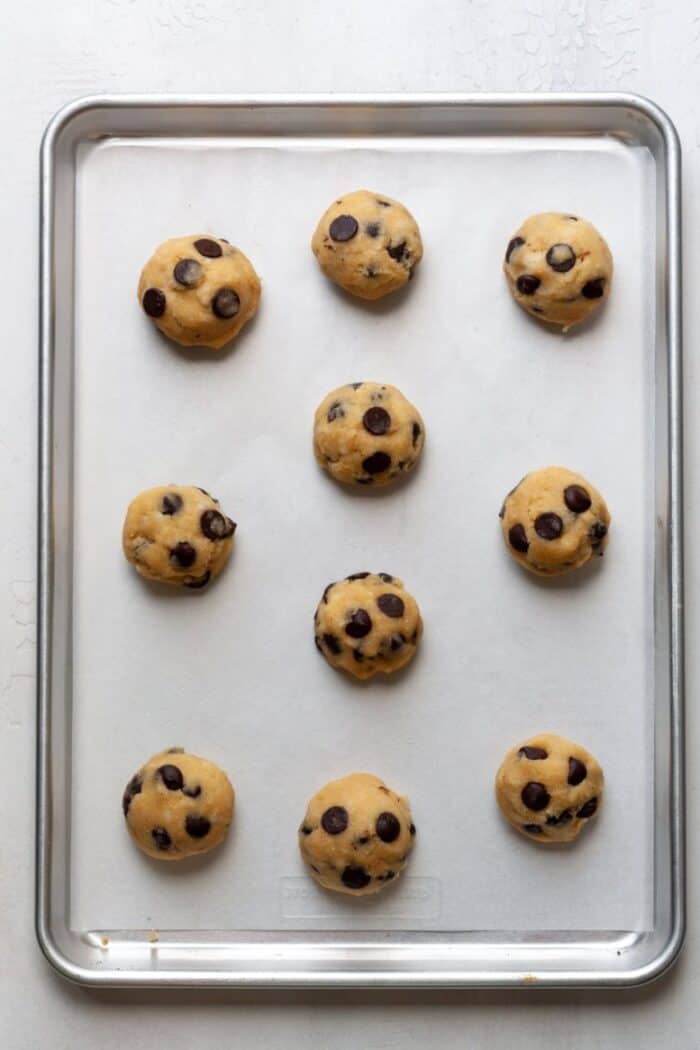 Balls of cookie dough on parchment lined baking pan