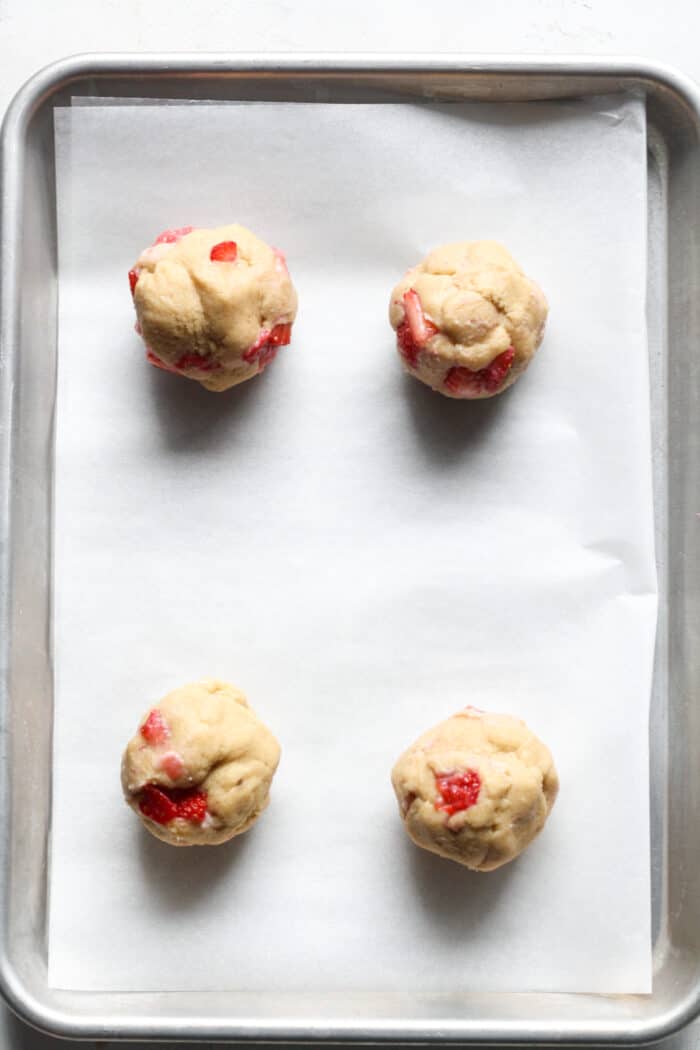 Balls of strawberry cookie dough on pan