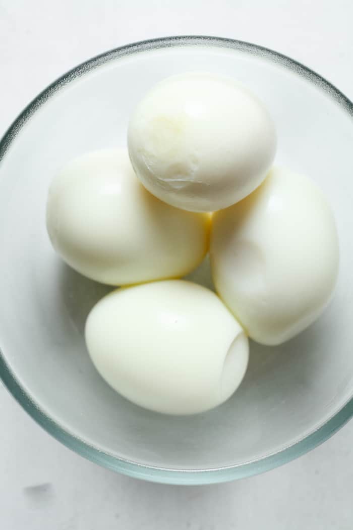 Peeled hard boiled eggs in bowl.