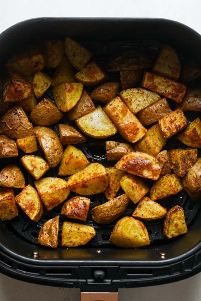 Air fryer basket with potatoes.