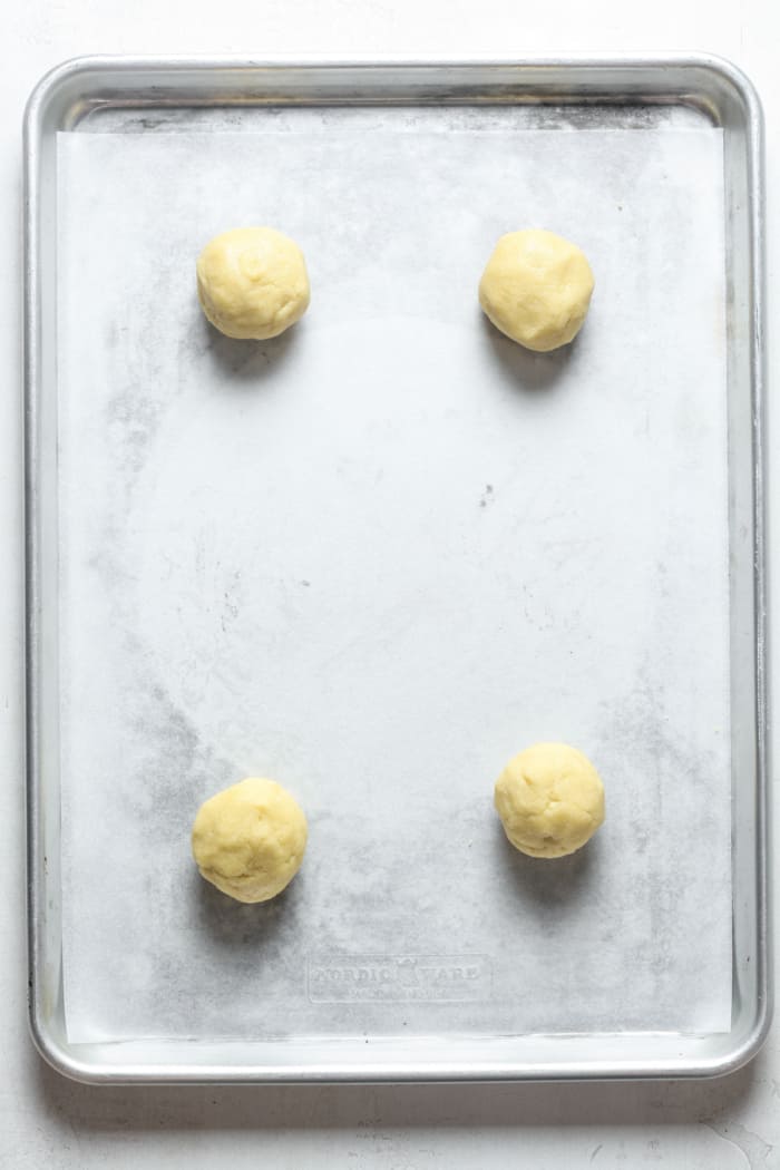 Four cookie dough balls on pan.