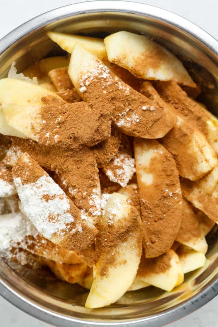 Apples, cinnamon and flour in bowl.