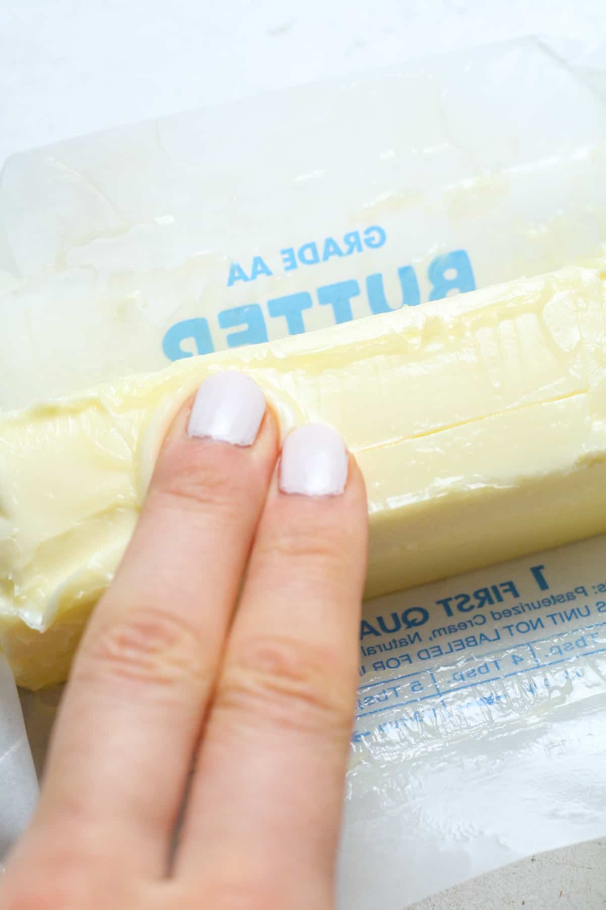 Fingers pressing into butter.