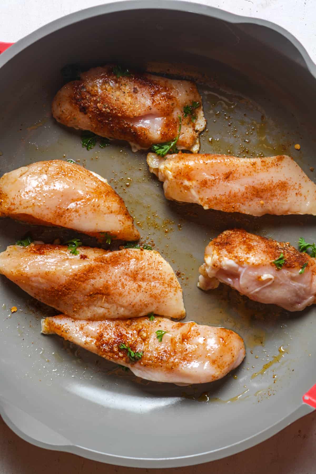 Seasoned chicken in skillet.