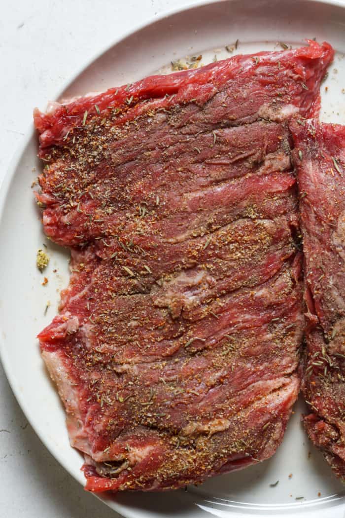 Seasoned steak on plate.