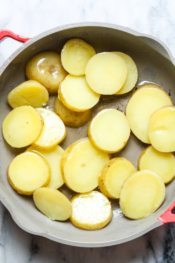 Sliced potatoes in skillet.
