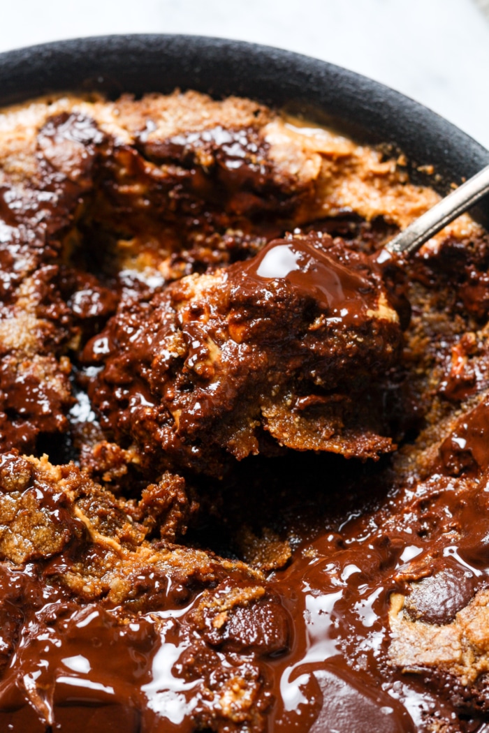 Spoon of gooey dessert in pan.